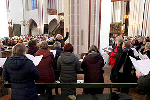 Männer und Frauen singen in einem Chor.