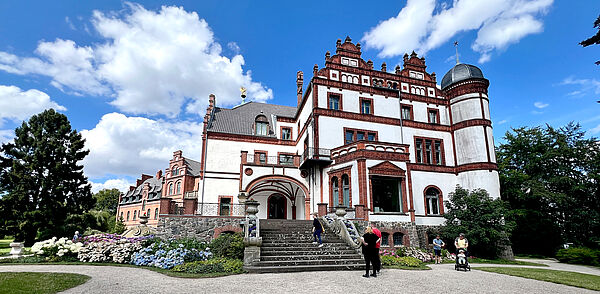 Schloss Wiligrad erhebt sich in seinem Park. Eine Treppe führt zum Eingan an einer weißen Fassade.