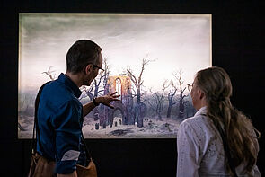 Zwei Gäste betrachten ein Bild in der Ausstellung.