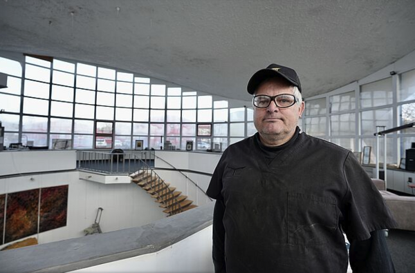 Ein dunkel gekleideter Mann steht in einem weiten Ausstellungsraum.