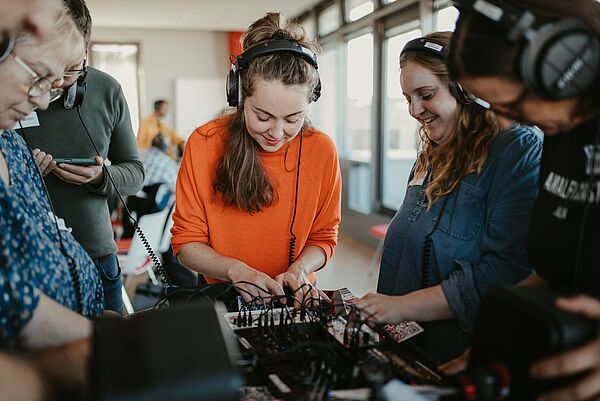 Studierende sitzen zusammen und musizieren digital.