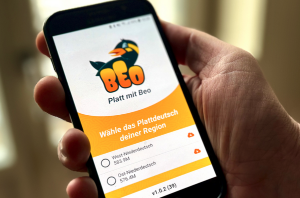 Ein Handy liegt in einer Hand. Geöffnet ist eine App: Platt mit Beo.