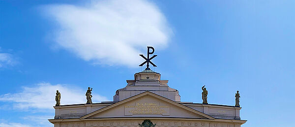 Das Dach der Stadtkirche. Auf dem Dach stehen vier Figuren. Und das Monogramm mit zwei griechischen Buchstaben. 