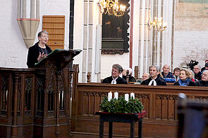 Eine Frau spricht auf der Kanzel einer Kirche.