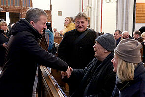 Ein Mann begrüßt einen Gast in einer Kirche.