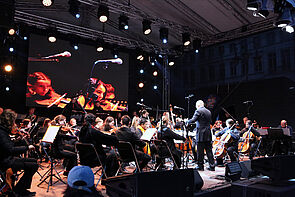 Blick auf die Bühne. Musikerinnen und Musiker spielen.