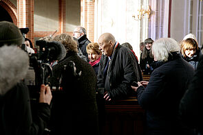 Begleitet von Kameras betritt ein Mann eine Kirche.