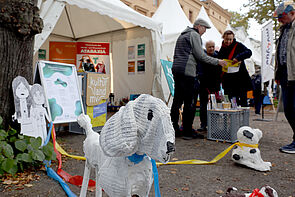 Kunstfiguren stehen vor einem Pavillon.