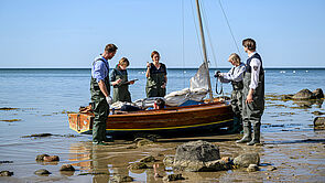 Am Ufer der Ostsee liegt ein Boot. Im Boot liegt eine Leiche. Das Ermittler-Team sichert den Tatort.